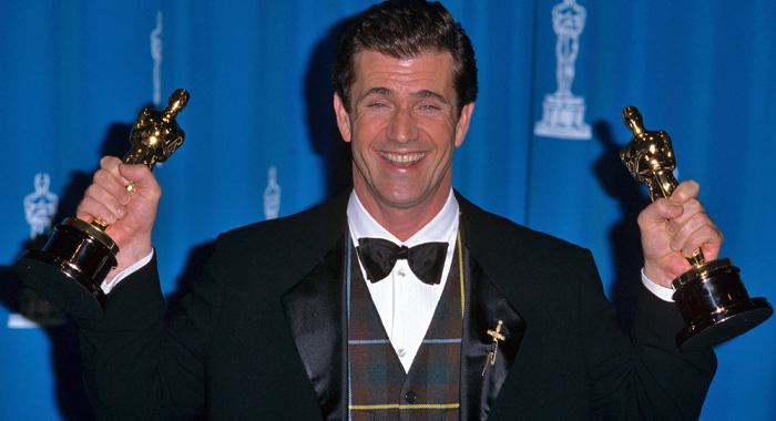 Mel Gibson holding up his two Oscar trophies from the 68th Academy Awards (1996)